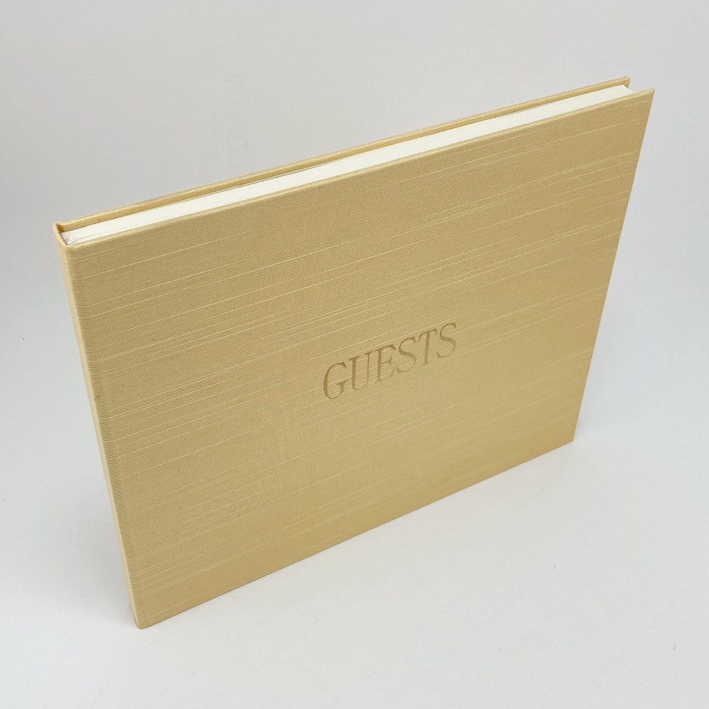 Gold silk covered book with 'GUESTS' embossed in foil on a light gray background