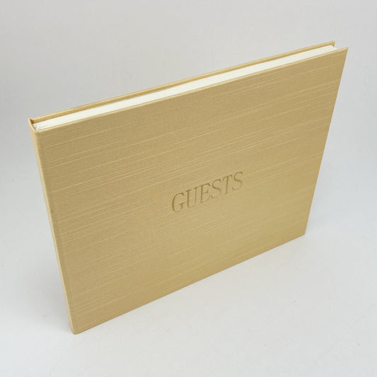 Gold silk covered book with 'GUESTS' embossed in foil on a light gray background